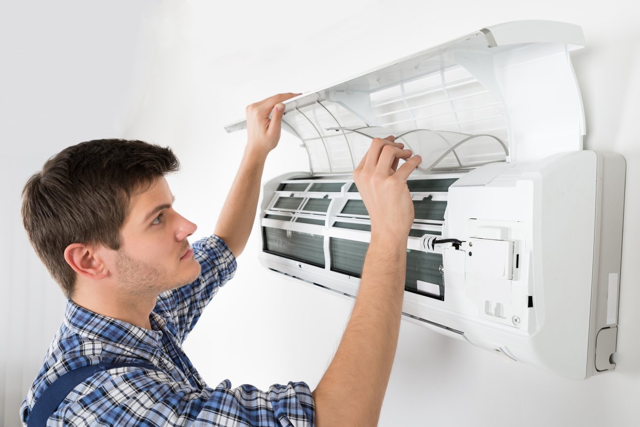 Young Male Technician Cleaning Air Conditioning System At Home